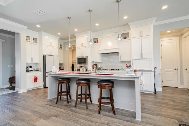 a kitchen with stainless steel appliances a sink a stove a refrigerator and island with wooden floor