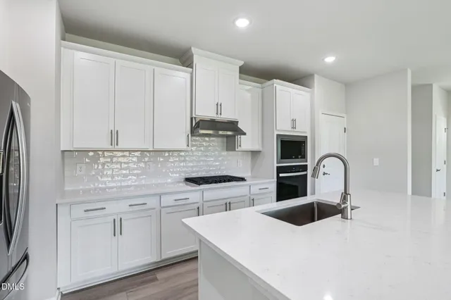 a kitchen with stainless steel appliances kitchen island granite countertop a stove and a refrigerator