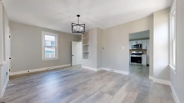 an empty room with wooden floor cabinet and windows