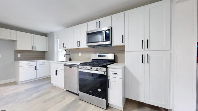 a kitchen with white cabinets and stainless steel appliances