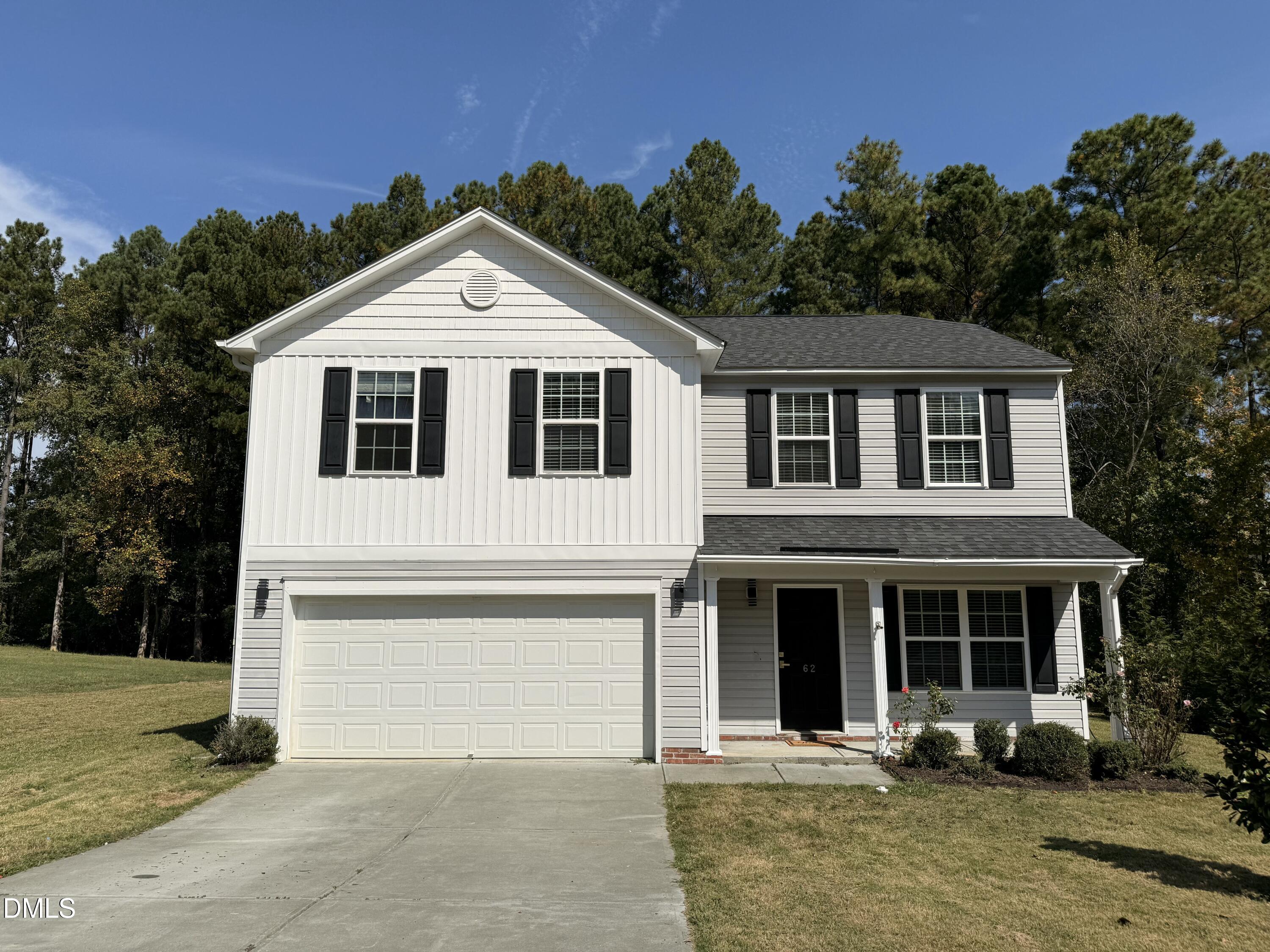 a front view of a house with yard and trees in the background
