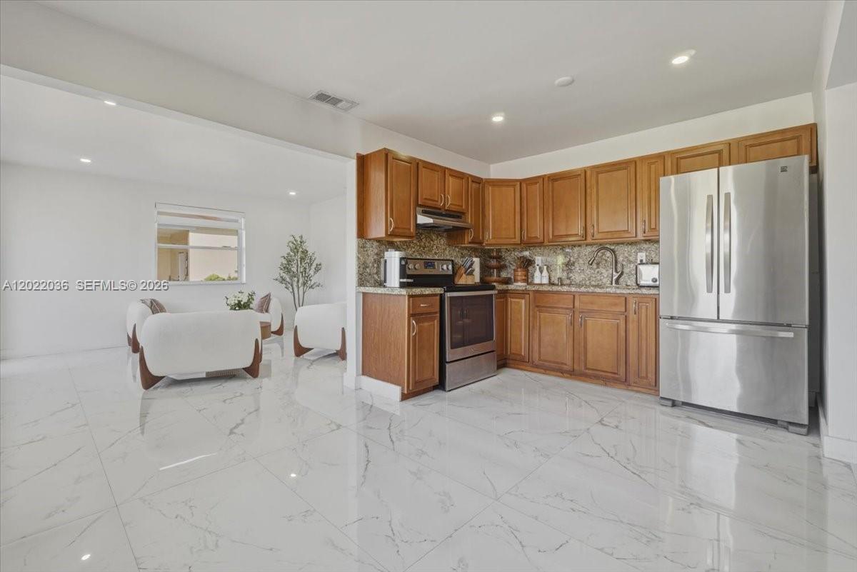 120 West 50th Street Hialeah, FL 33012 - Photo 9 of 22 a kitchen with stainless steel appliances granite countertop a stove top oven a sink and a refrigerator