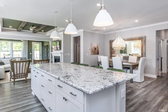 a view of living room kitchen with granite countertop wooden floor and stainless steel appliances