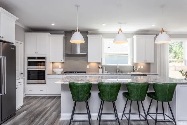 a kitchen with kitchen island granite countertop a sink and white cabinets