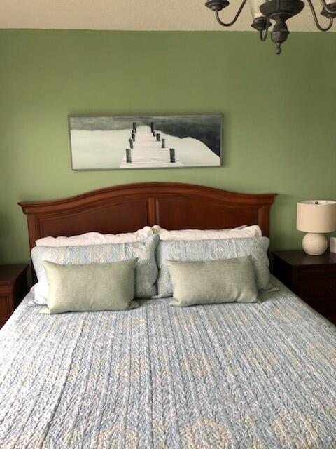 6021 Southeast Landing Way, Unit BLDG 2 #2 Stuart, FL 34997 - Photo 17 of 35 a bed sitting in a bedroom with a lamp