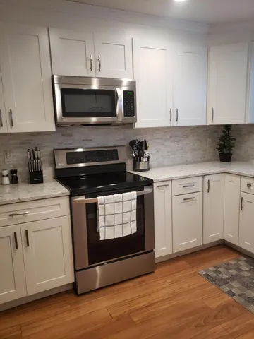 a kitchen with granite countertop white cabinets and stainless steel appliances