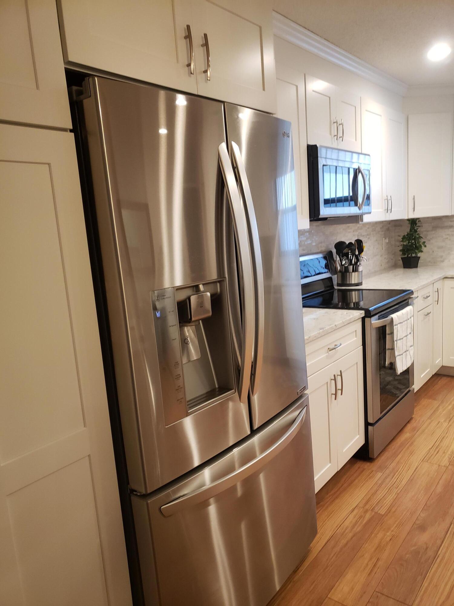 6021 Southeast Landing Way, Unit BLDG 2 #2 Stuart, FL 34997 - Photo 3 of 35 a kitchen with stainless steel appliances a refrigerator a sink a stove a microwave and cabinetry