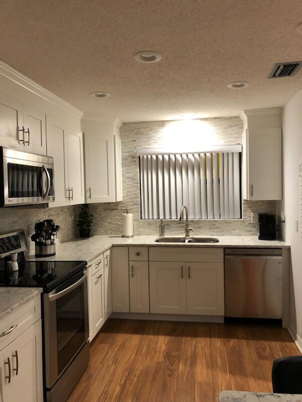 6021 Southeast Landing Way, Unit BLDG 2 #2 Stuart, FL 34997 - Photo 4 of 35 a kitchen with granite countertop a sink and cabinets
