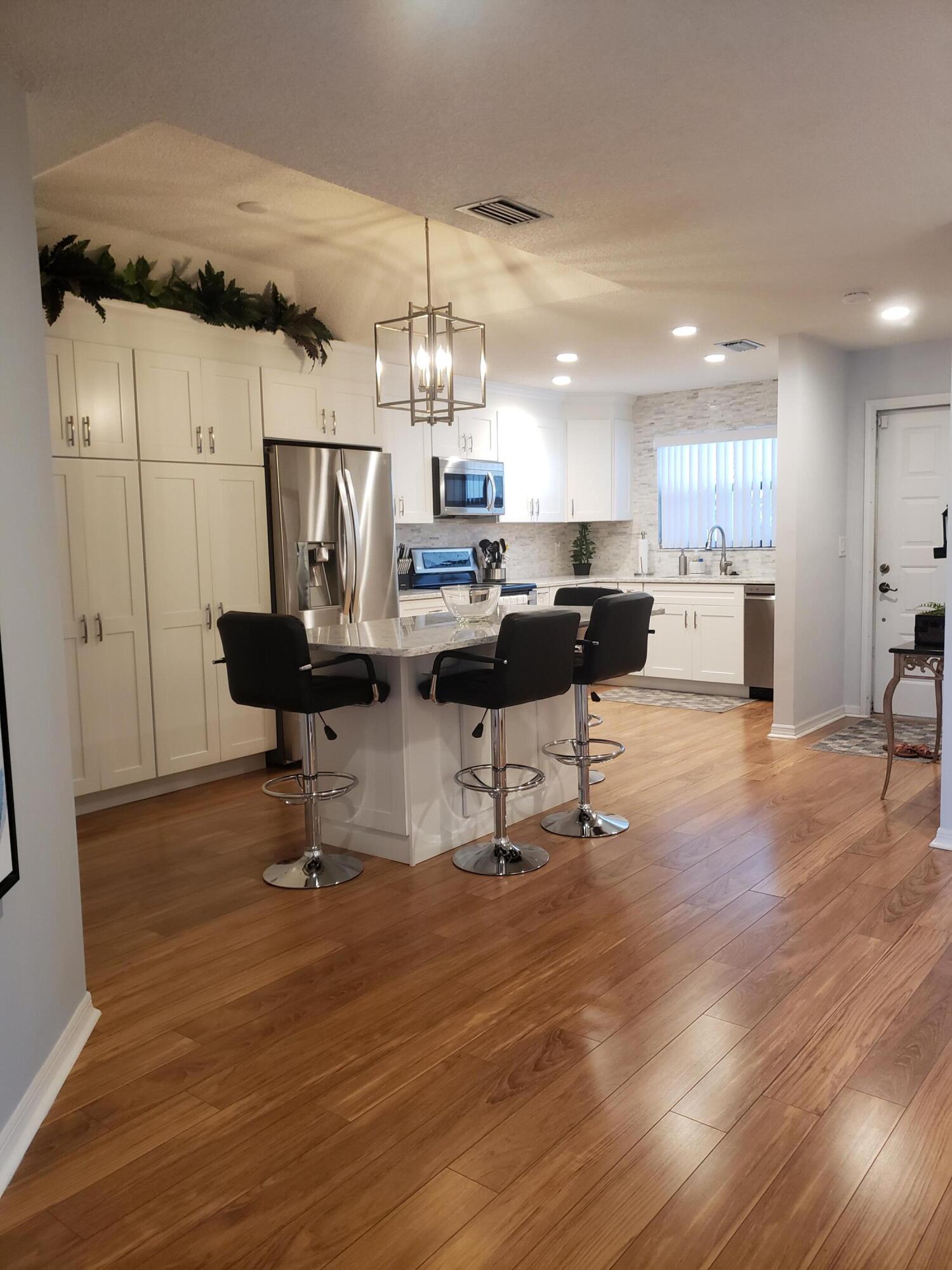 6021 Southeast Landing Way, Unit BLDG 2 #2 Stuart, FL 34997 - Photo 5 of 35 a living room with furniture and a chandelier