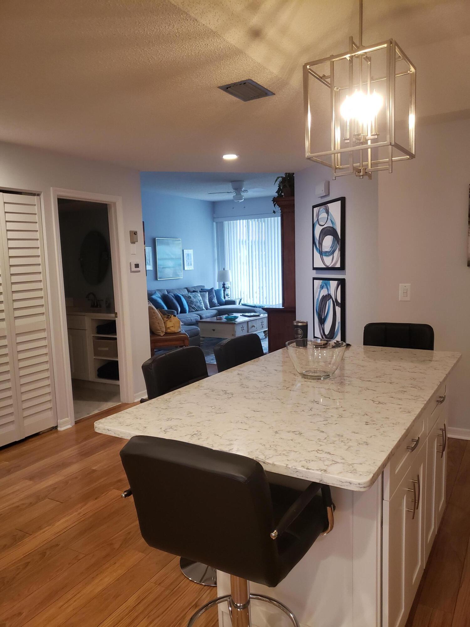 6021 Southeast Landing Way, Unit BLDG 2 #2 Stuart, FL 34997 - Photo 10 of 35 a kitchen with stainless steel appliances kitchen island granite countertop a table chairs in it and wooden floors