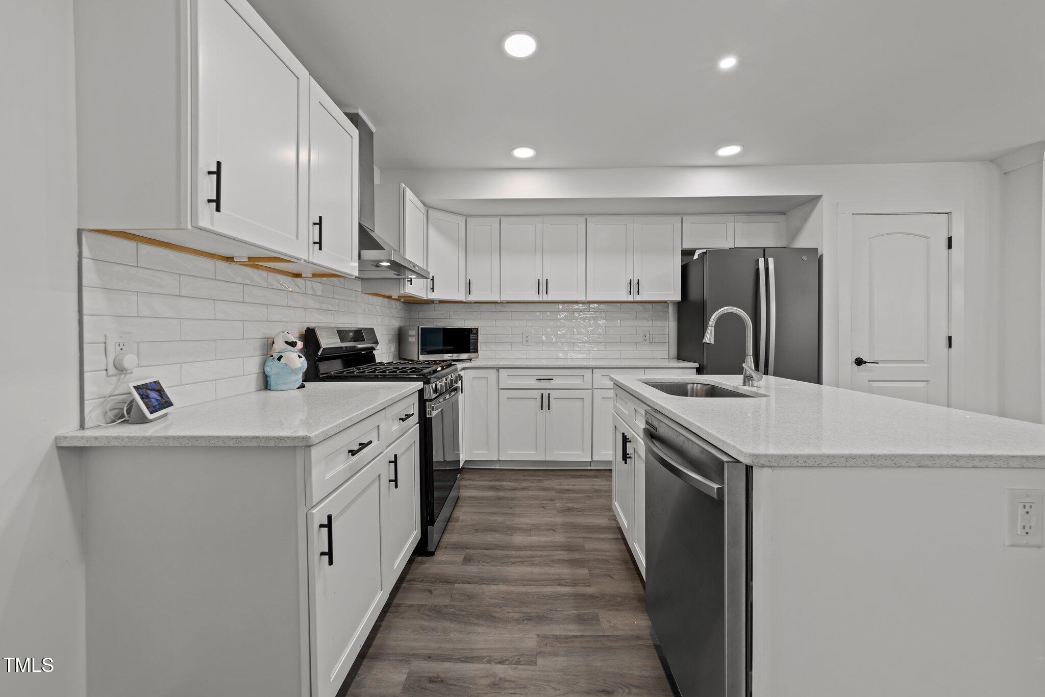 819 Cumberland Street Raleigh, NC 27610 - Photo 13 of 32 a kitchen with a sink a stove top oven and white cabinets