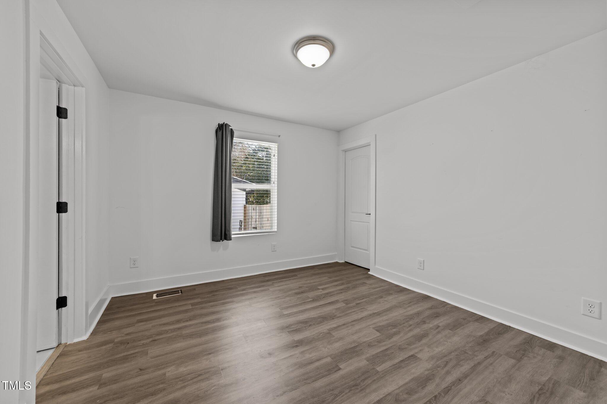 819 Cumberland Street Raleigh, NC 27610 - Photo 19 of 32 a view of an empty room with wooden floor and a window