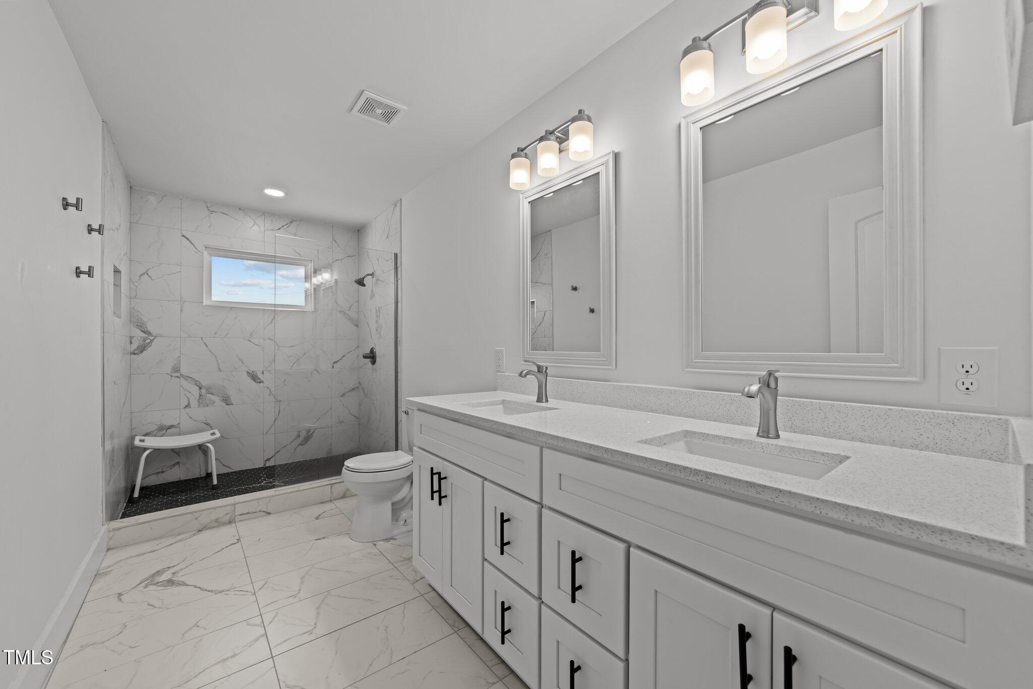 819 Cumberland Street Raleigh, NC 27610 - Photo 26 of 32 a spacious bathroom with a double vanity sink a toilet and a mirror