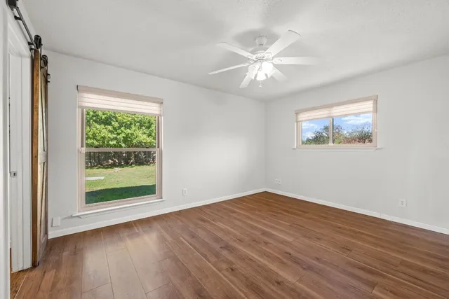 a view of empty room with wooden floor and fan