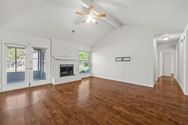 a view of an empty room with window and wooden floor