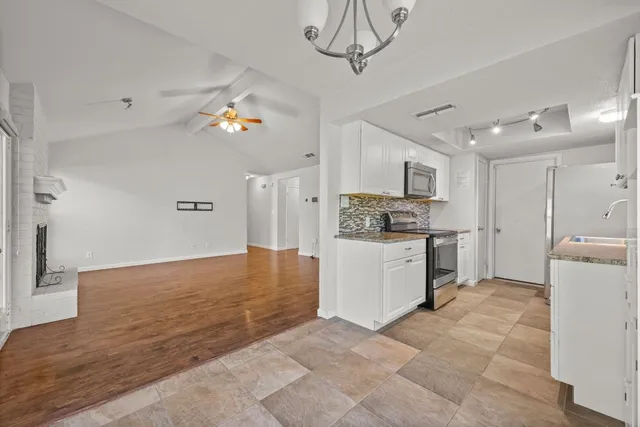 a view of a kitchen with a sink and dishwasher a refrigerator with white cabinets