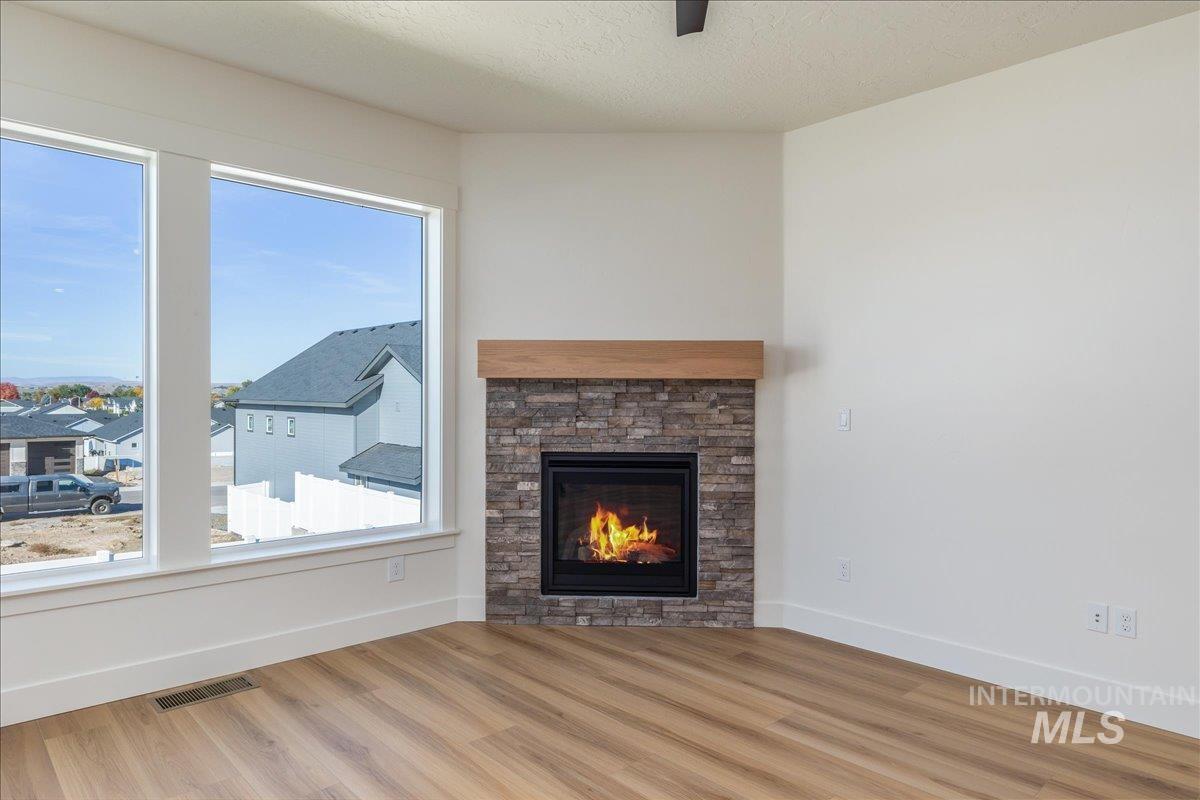 775 Pinehurst Street Payette, ID 83661 - Photo 12 of 36 Unfurnished living room with plenty of natural light, a fireplace, wood finished floors, and a textured ceiling