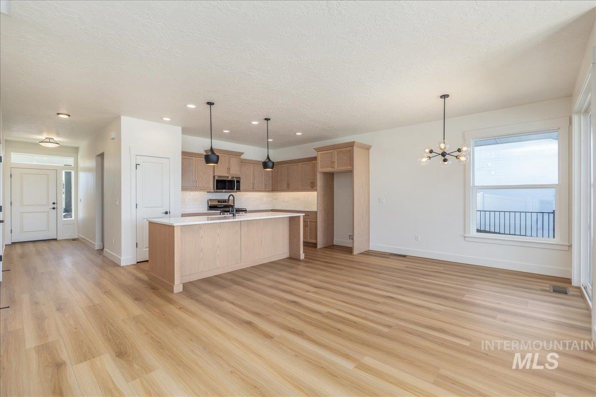 775 Pinehurst Street Payette, ID 83661 - Photo 13 of 36 Kitchen with pendant lighting, light wood-style floors, an island with sink, a chandelier, and a textured ceiling