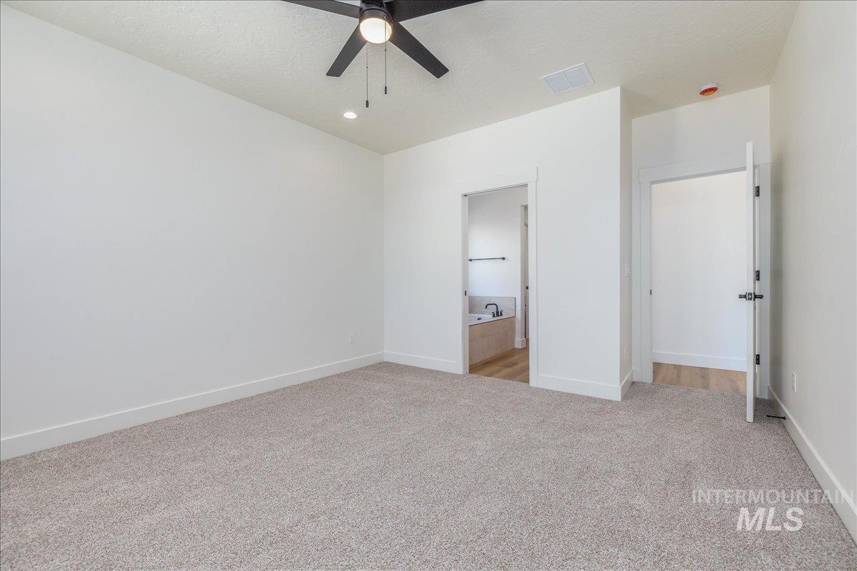 775 Pinehurst Street Payette, ID 83661 - Photo 19 of 36 Unfurnished bedroom featuring light colored carpet, ensuite bathroom, a textured ceiling, and ceiling fan