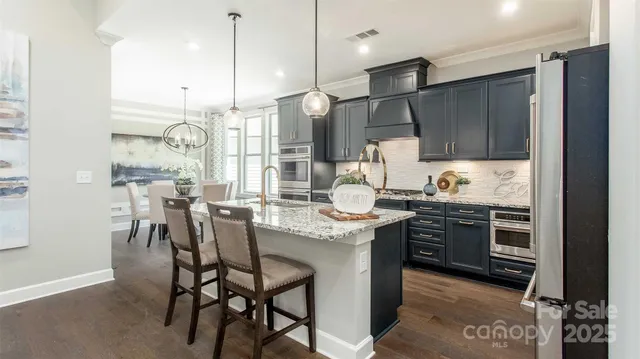 a kitchen with stainless steel appliances granite countertop a sink a stove and a refrigerator