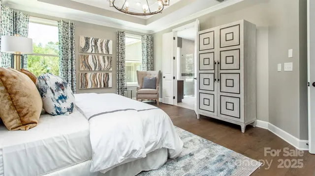 a spacious bedroom with a bed a dresser and a large window