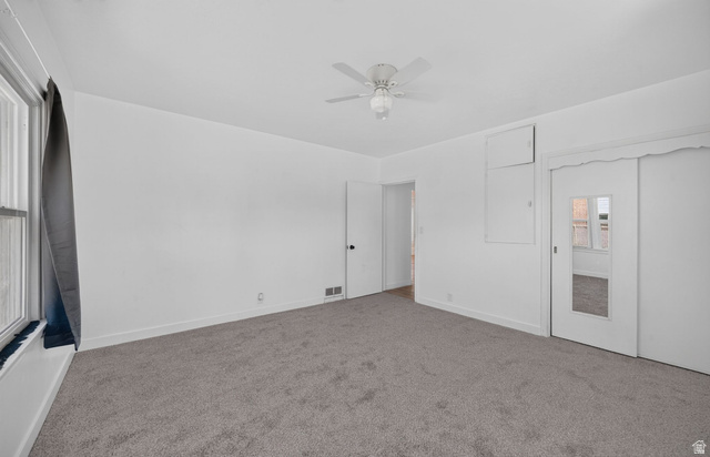 220 East Greenwood Avenue Midvale, UT 84047 - Photo 15 of 46 Spacious interior room featuring gray carpet flooring, white walls, and a ceiling fan with integrated lighting