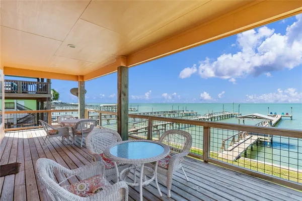 a view of a balcony with dining table and chairs with wooden floor & fence