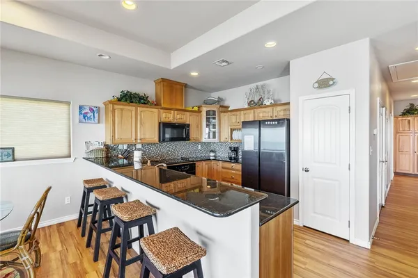 a kitchen with stainless steel appliances granite countertop a refrigerator a stove a sink a dining table and chairs with wooden floor