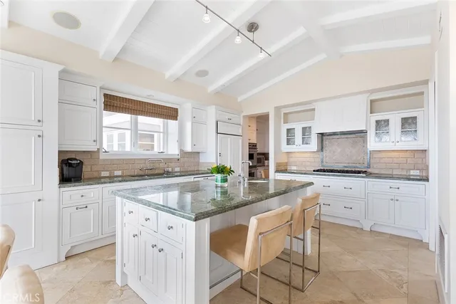 a kitchen with stainless steel appliances granite countertop a stove a sink and white cabinets