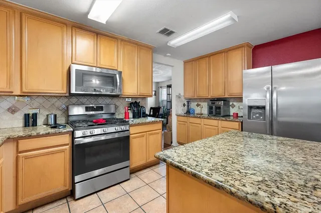 a kitchen with kitchen island granite countertop a stove top oven microwave and refrigerator