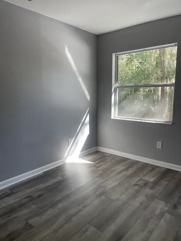 an empty room with wooden floor and windows