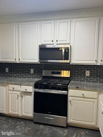a kitchen with granite countertop white cabinets and stainless steel appliances