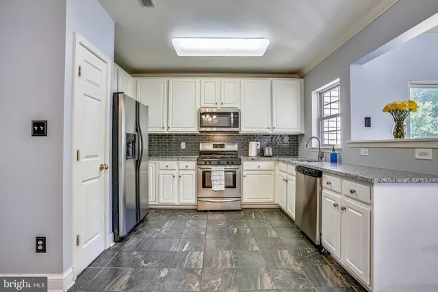 a kitchen with granite countertop a refrigerator and a stove top oven