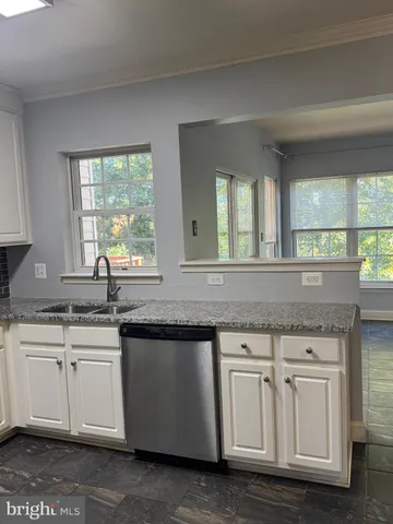 a kitchen with white cabinets and sink