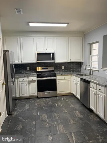 a white kitchen with granite countertop a stove top oven sink and cabinets