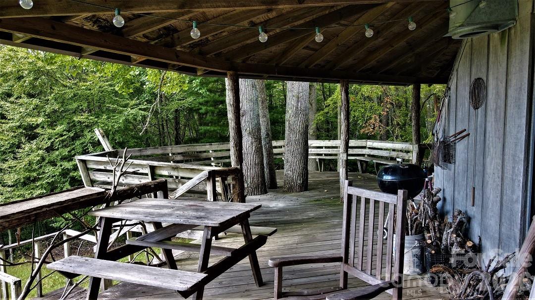 745 Broom Road Tuckasegee, NC 28783 - Photo 12 of 42 a view of a patio with table and chairs a barbeque with wooden floor and roof with a garden view