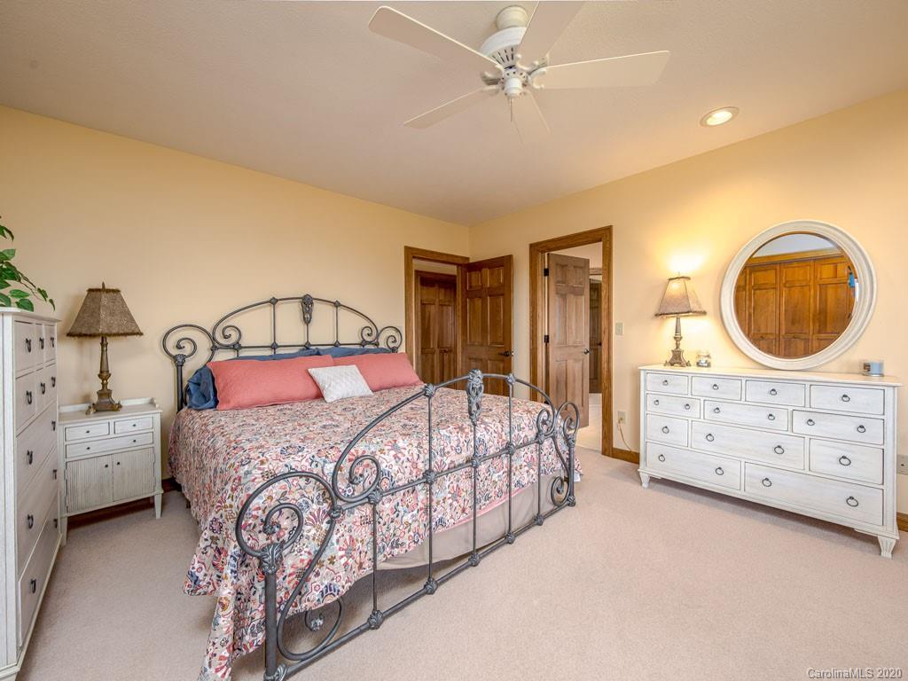 270 Country Ridge Road Laurel Park, NC 28739 - Photo 25 of 39 a bedroom with a bed a mirror on dresser and a chandelier