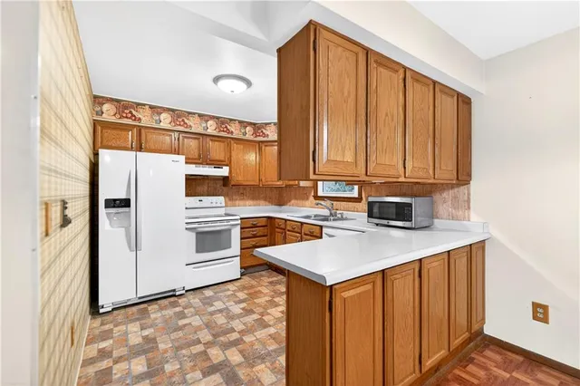 a kitchen with stainless steel appliances granite countertop a refrigerator a sink dishwasher a stove with white cabinets and wooden floor