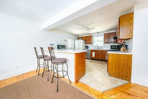 12 Pinehurst Drive Monument Beach, MA 02532 - Photo 8 of 31 a kitchen with stainless steel appliances granite countertop a stove top oven a sink a dining table and chairs with wooden floor
