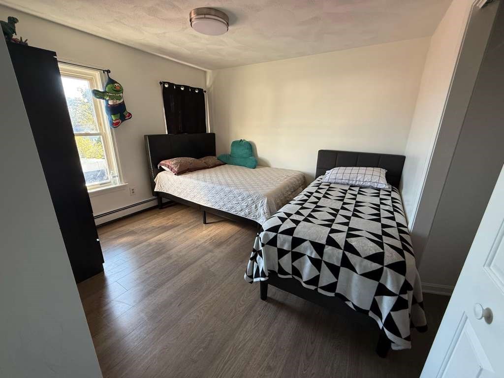 642-648 Eastern Avenue, Unit 3 Lynn, MA 01902 - Photo 5 of 7 a bedroom with a bed and wooden floor