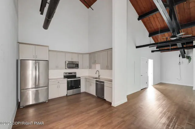 a kitchen with stainless steel appliances wooden floor sink and stove