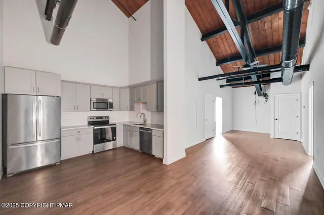a kitchen with stainless steel appliances a refrigerator and wooden floor