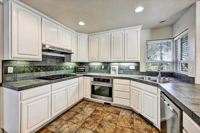 an empty room with wooden floor chandelier fan and windows