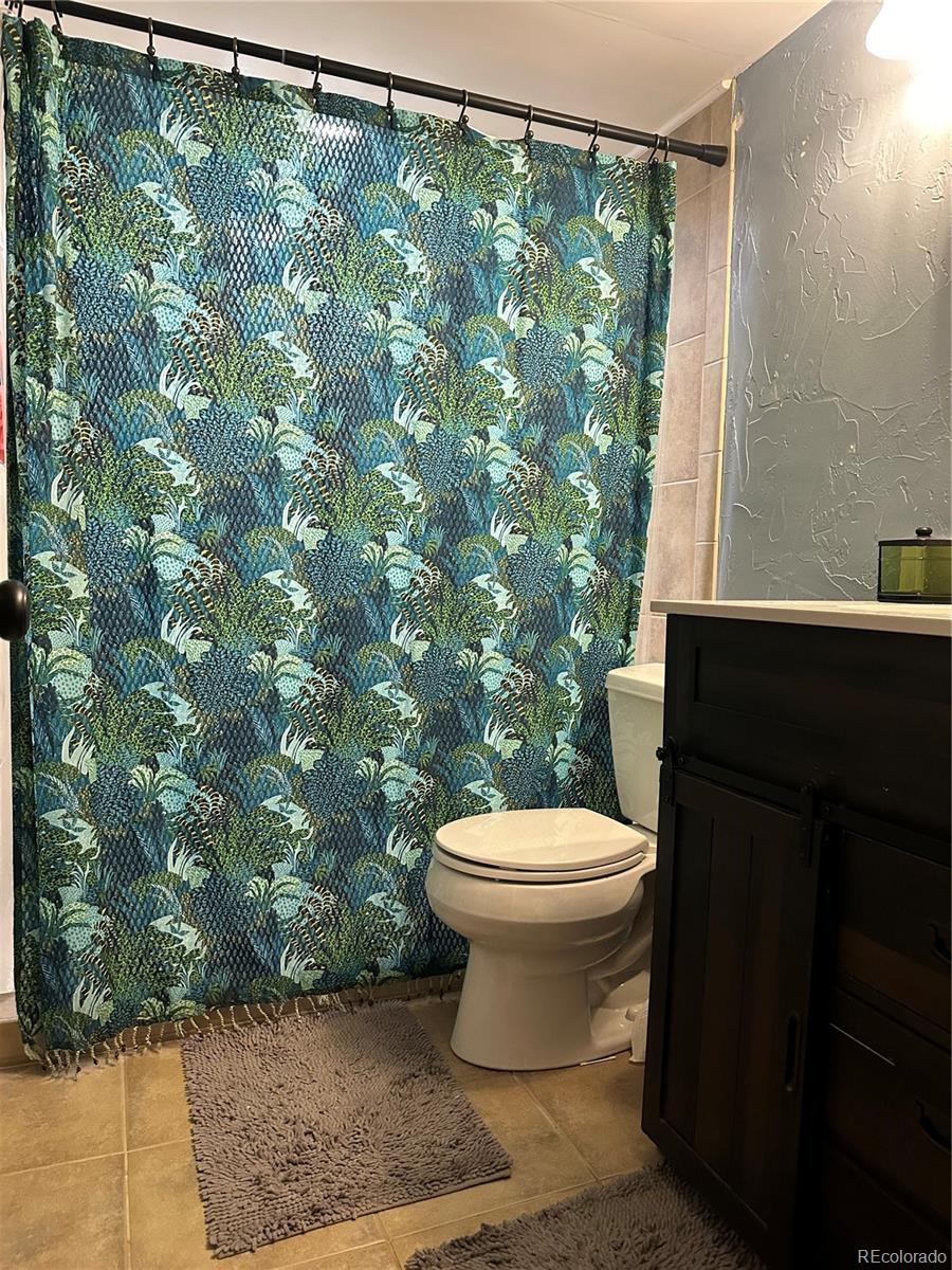 6614 Gray Street Arvada, CO 80003 - Photo 16 of 19 a white toilet sitting next to a shower curtain