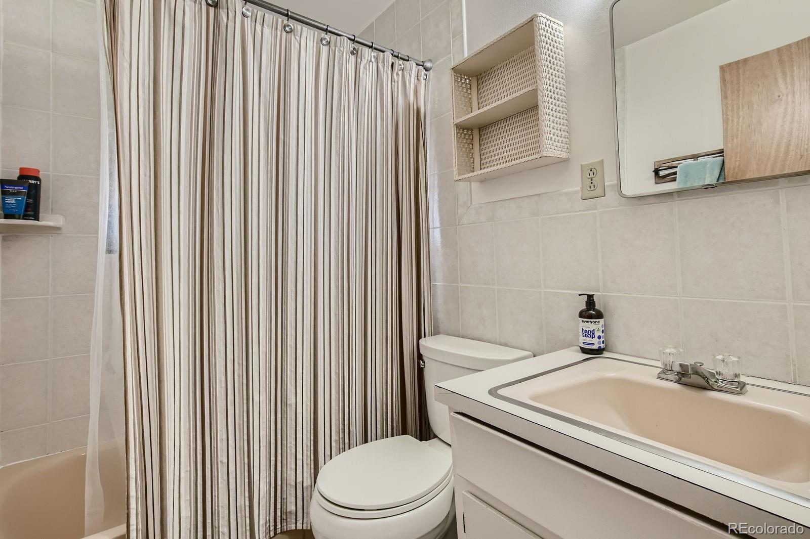 6614 Gray Street Arvada, CO 80003 - Photo 6 of 19 a bathroom with a sink a toilet and shower curtain