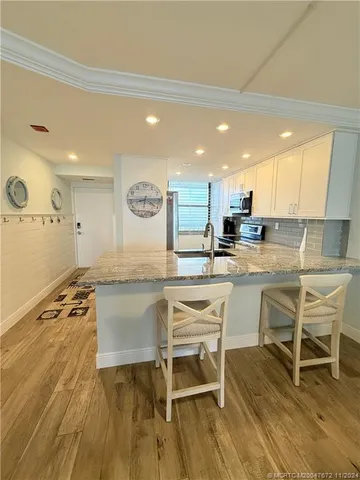 a kitchen with a table chairs wooden floors and a view of living room