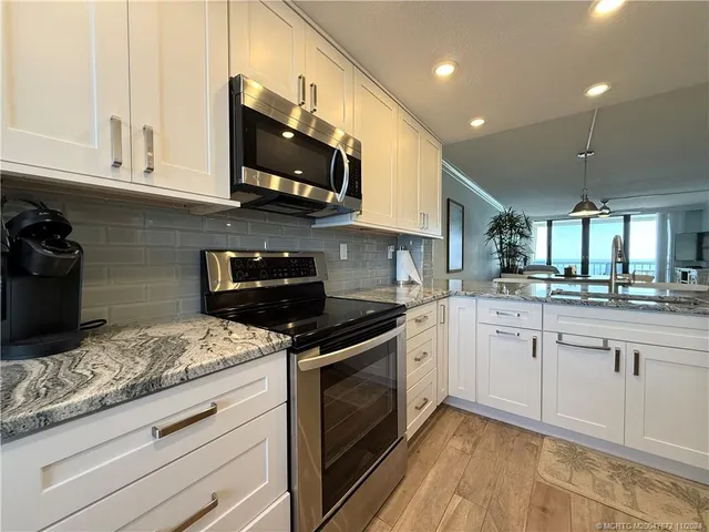 a kitchen with stainless steel appliances granite countertop a sink a stove and a microwave