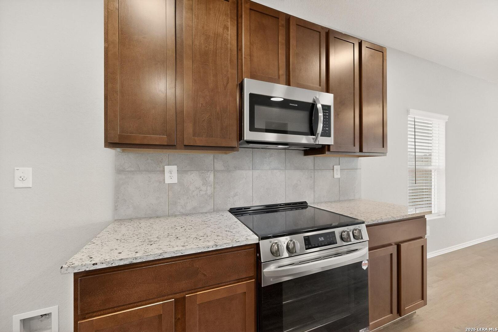 3038 Laguna Cliffs Converse, TX 78109 - Photo 11 of 32 a kitchen with granite countertop cabinets stainless steel appliances and wooden floor