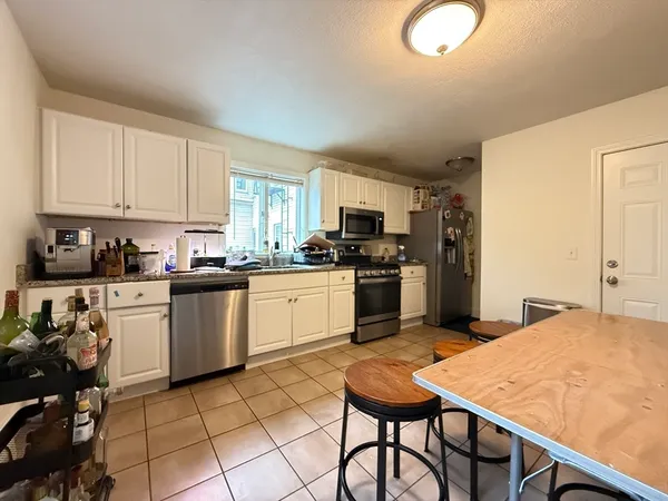 a kitchen with a refrigerator a stove top oven a sink dishwasher and white cabinets with wooden floor