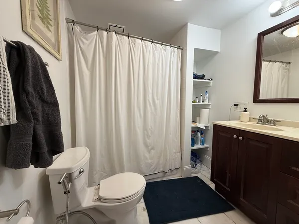 a bathroom with a sink a toilet a mirror and shower curtain